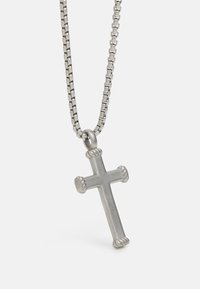 Pendentif croix en métal argenté avec des accents en corde, attaché à une chaîne à maillons ronds. Surface lisse, design simple.