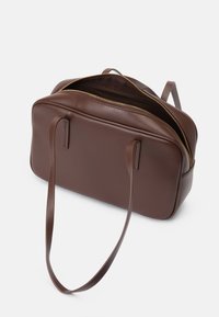 Brun skinn toteveske med rektangulær fasong, har glidelås, to håndtak og en glatt tekstur. Innvendig er den uten fôr.