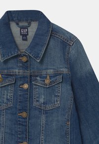 Modrá džínová bunda s měděnými knoflíky, dvěma náprsními kapsami s klopami, kontrastním oranžovým šitím a ohrnutým límcem.