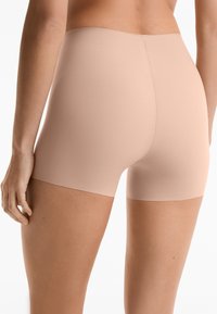 Beige stretch shorts met een gladde, naadloze afwerking. De stof is lichtgewicht en ze hebben een snit tot halverwege de dij met een subtiele glans.