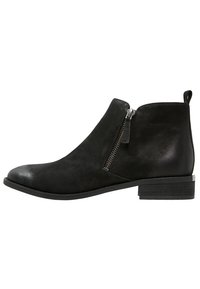 Bottine en cuir noir avec un bout arrondi, fermeture éclair sur le côté et un petit talon carré. Texture lisse avec un design minimaliste.