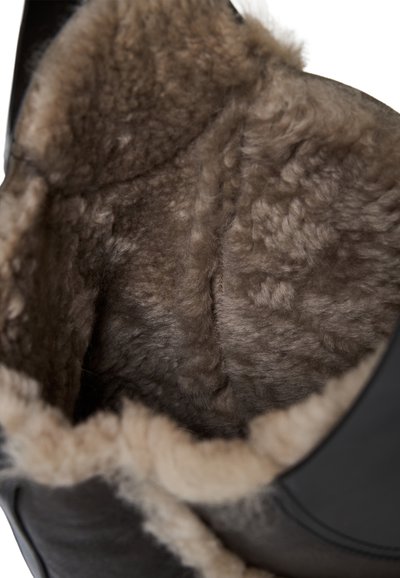 Stivale nero con fodera in morbido pelo marrone. Il materiale sembra liscio, con un'apertura arrotondata e un bordo testurizzato. Nessun hardware visibile.