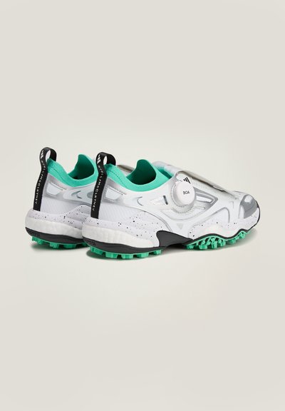 Zapatillas deportivas blancas con un upper texturizado, que presentan detalles en verde menta, forro de malla y un sistema de cordones Boa. Suela verde con clavos para tracción.