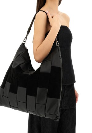 Borsa a tracolla intrecciata nera che presenta una combinazione di pelle texturizzata e camoscio, con una forma morbida e una tracolla regolabile. Accenti in metallo argentato.