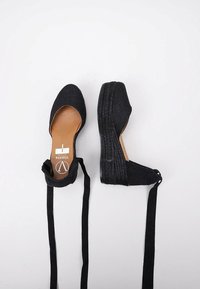 Zapatos espadrilles negros con plataforma de yute trenzado, parte superior de lona y largas cintas de tela para el ajuste en el tobillo. Forro interior suave.