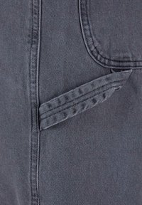 Tmavě šedá tkanina s hladkým povrchem, která obsahuje čistě prošitou kapsu a detail skládaného klopového okraje.