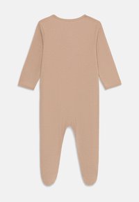 Ribbed long-sleeve onesie in a soft beige color. Features rounded neckline and footed design with a smooth texture. No visible hardware.