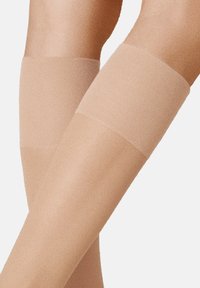 Beige Strümpfe bis zum Oberschenkel mit glatter Textur und elastischen Bündchen. Das durchsichtige Material reicht bis zur Mitte des Oberschenkels und ist für Komfort und Passform ausgelegt.