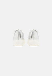 Sølvfargede metalliske sneakers med glatt tekstur, rund tå og hvit gummisåle. Minimalistisk design uten synlig merkevare på baksiden.
