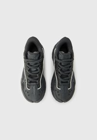 Ζευγάρι μαύρα αθλητικά παπούτσια με κορδόνια, πλαϊνά από δίχτυ και σχεδιασμένες λεπτομέρειες, σε θέα από πάνω σε απλό ανοιχτό φόντο.