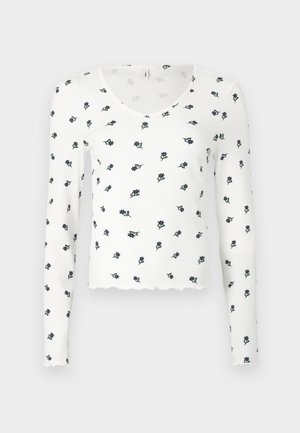 Pikem varrukaga valge särk, millel on ribatakstuur, skaalapoolses lõikes ja sinise ning rohelise lillelise mustriga.