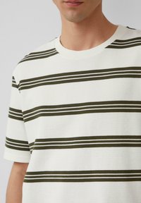 Gestreepte t-shirt in het wit met olijfgroene en dunne witte strepen. Geribbelde textuur, ronde hals en korte mouwen.