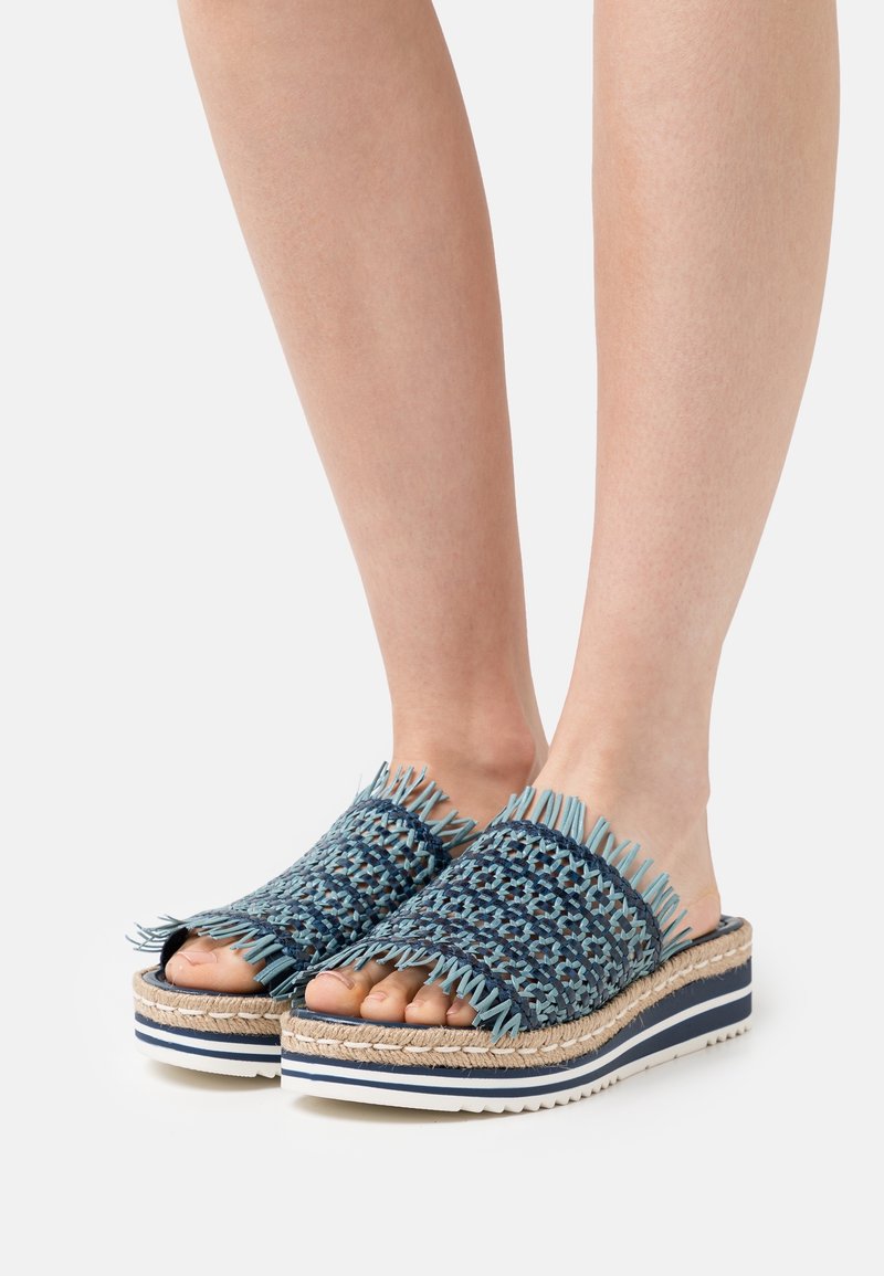 Blå vävda slidesandaler med fransdetaljer, som har en texturerad ovandel, plattformsula med espadrille-liknande design och randiga accenter.