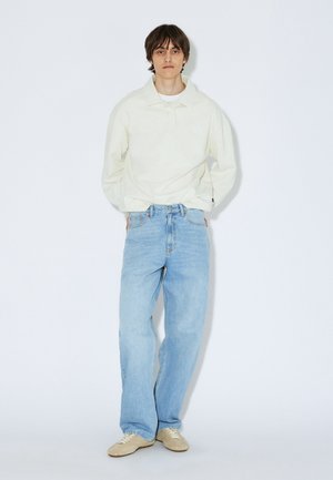 Lyse beige poloshirt med lange ærmer, lyseblå jeans med lige ben, beige sko. Simpelt design, blød tekstur og minimal detaljering.