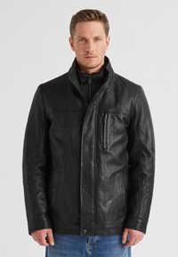Schwarze Lederjacke mit hohem Kragen, Reißverschluss und Brusttasche. Glatte Textur mit Seitentaschen und strukturierten Nähten.
