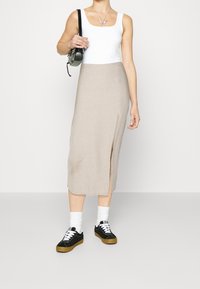 Bílý tílko, béžová sukně ke kolenům s bočním rozparkem, doplněná černými teniskami a bílými ponožkami. Malá černá kabelka, náhrdelník ve tvaru motýla.