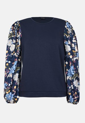 Marineblå hettegenser med blomsterdekorert pufferm i nyanser av blått, rosa og gult. Jevn tekstur med rund hals og ribbestrikkede mansjetter.