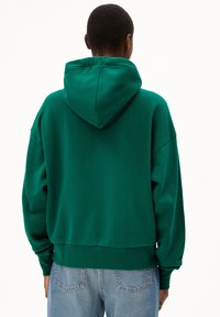 Grüner, gekürzter Hoodie mit Kapuze, übergroßen Ärmeln und weicher Textur. Besitzt einen gerippten Saum und Bündchen, kombiniert mit hellblauer Denim.