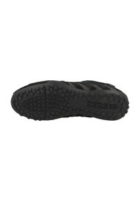 Sneaker nera con suola in gomma testurizzata dotata di impugnature circolari. La parte superiore è realizzata con una combinazione di materiali lisci e a fantasia.
