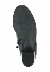 Suela de zapato de cuero negro con patrón de agarre texturizado y un leve tacón. Detalle de cremallera lateral con superficie lisa y diseño de punta redondeada.