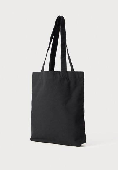 Black canvas tote bag with long, flat handles. Simple, unadorned design with a rectangular shape and soft texture.
