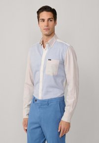 Lichtblauwe en crèmekleurige overhemd met knoopjes, voorzien van een borstzak en contrasterende mouwen, gedragen met blauwe broek. Katoenen stof, casual pasvorm.