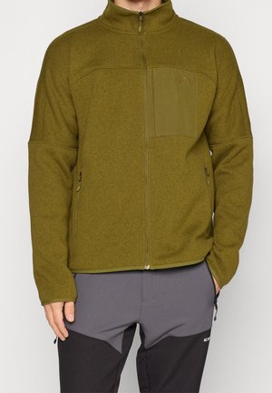 Oliivinvihreä fleece-takki, jossa on korkea kaulus, vetoketjullinen etuosa, rintatasku ja sivutaskut; teksturoitu kangas, jossa on sileä pinta.