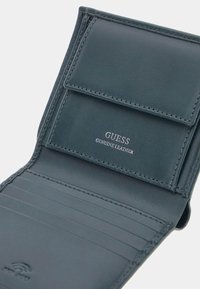 Green genuine leather wallet featuring a card holder, multiple slots, and a flap closure with embossed branding. Smooth texture throughout.