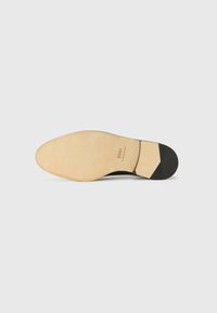 Black leather shoe sole with a light beige finish, rubber heel accents, and textured lines for grip. Brand name "BOSS" embossed.