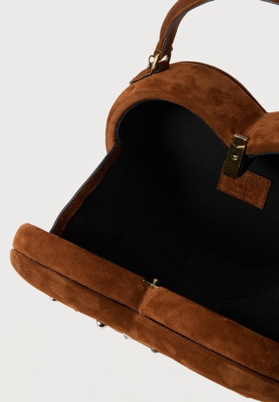 Sac à main en daim marron avec une poignée incurvée, une doublure intérieure noire et une fermeture à fermoir doré sur un fond uni.