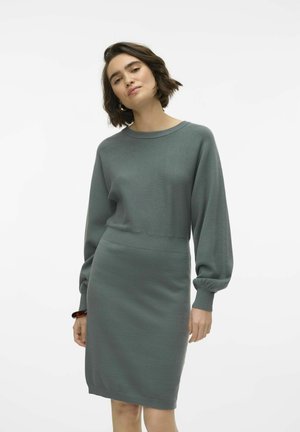 Robe pull en vert doux, avec un col rond, des manches ballons longues et une silhouette ajustée. Tissu tricoté avec des accents côtelés.