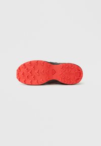 Σόλα παπουτσιού για τρέξιμο σε μονοπάτια, με κόκκινη εξωτερική σόλα από καουτσούκ με στίγματα και τριγωνικά πέλματα, καθώς και μαύρο ανώτερο άκρο, σχεδιασμένη για πρόσφυση και κράτημα.