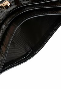 Zwarte binnenkant van een neplederen tas, met een gladde textuur en een subtiel rasterpatroon. Gouden hardware-accent zichtbaar bij de rand.