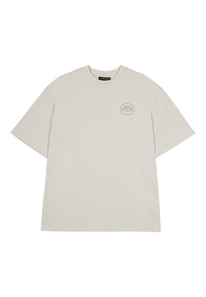 Bomulds T-shirt i lys grå med rund hals, korte ærmer og et lille cirkulært logo på venstre brystområde. Enkel, afslappet pasform.
