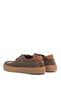 Braune Wildlederschuhe mit Gummisohle, runder Zehenform, braunen Lederapplikationen am Absatz und Schnürverschluss mit dunkelbraunen Schnürsenkeln.
