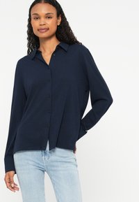 Chemise bleu marine à boutons, avec col, manches longues et coupe décontractée, fabriquée dans un tissu doux, dotée d'un détail d'ourlet fendu.