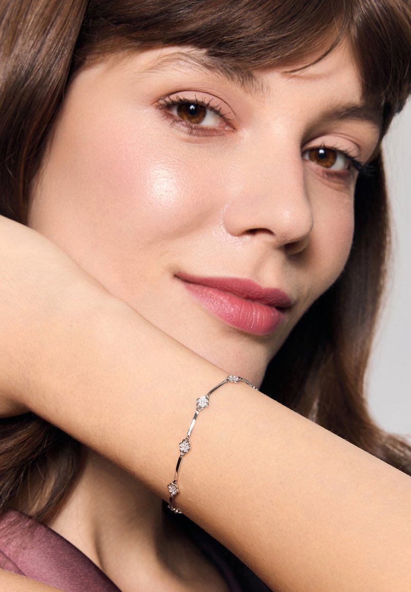 Srebrna bransoletka z pięcioma akcentami w kształcie kwiatów, z przezroczystymi kamieniami. Projekt jest delikatny, z polerowanym wykończeniem i subtelnym połyskiem.