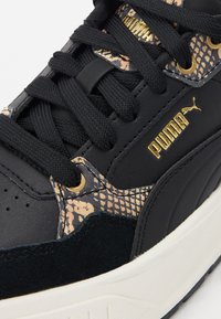 Black sneakers featuring a textured snake-print accent, gold hardware, and black laces. Soft suede and smooth leather materials.
