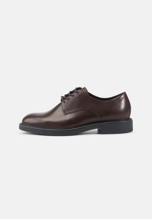 Dunkelbrauner Herrleder-Halbschuh mit schwarzer Sohle und Schnürsenkeln, seitlich auf einem einfachen hellen Hintergrund dargestellt.
