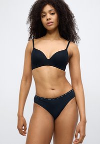 Sort sømløs bh med justerbare stropper og U-formet udskæring. Matchende sort bikini med elastik i taljen med mærke. Glat tekstur.