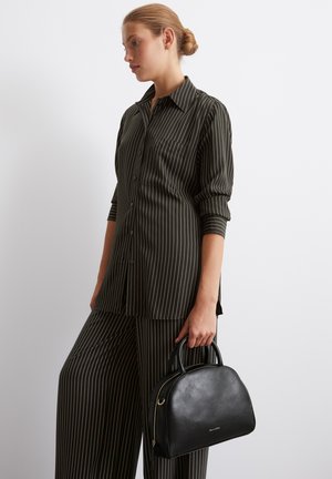 Schwarze Lederhandtasche mit abgerundetem oberen Teil, doppelten Griffen und Reißverschluss. Das Design zeichnet sich durch minimale Hardware und eine glatte Textur aus.