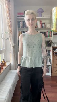 Šviesiai žalia be rankovių palaidinė su peplum apdaila, puošta skylutėmis. Derinama su juodomis krovinių kelnėmis su šoninėmis kišenėmis ir diržais.