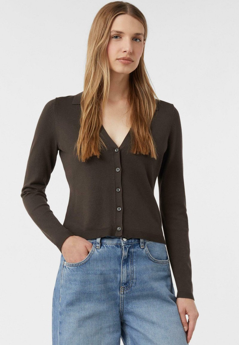 Brauner, gestrickter Cardigan mit V-Ausschnitt, Knopfverschluss vorne, langen Ärmeln und geripptem Saum, kombiniert mit hellblauen Jeans.