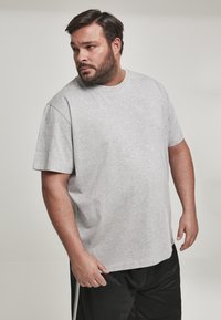 T-shirt en coton gris avec un col rond et des manches courtes, offrant une coupe décontractée et une texture lisse, assortie à un short noir.