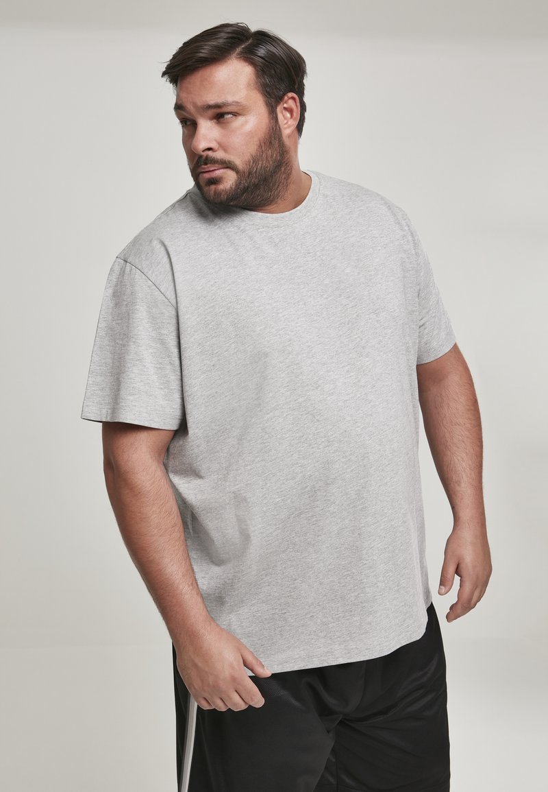 T-shirt en coton gris avec un col rond et des manches courtes, offrant une coupe décontractée et une texture lisse, assortie à un short noir.