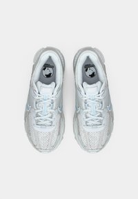 Sapatilhas desportivas leves em branco com detalhes em prata, apresentando uma superfície texturizada, cordões redondos e uma sola almofadada.