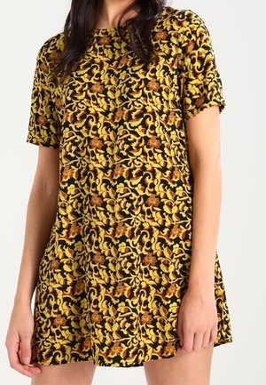 Zwart jurkje met korte mouwen en een geelbruine bloemprint. Heeft een losse pasvorm, zachte stof en een eenvoudige ronde halslijn.