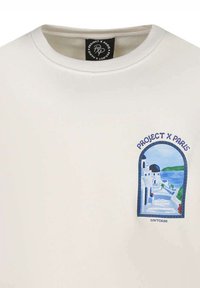 Sudadera blanca con cuello redondo y un estampado gráfico que representa un edificio con cúpula azul y escaleras junto al mar. El texto dice "PROJECT X PARIS."