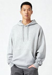 Felpa con cappuccio grigia realizzata in tessuto morbido, dotata di tasca frontale, coulisse regolabili e polsini e orlo a coste. Vestibilità casual.