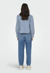 Giubbotto di jeans blu chiaro con maniche a sbuffo, orlo corto e jeans larghi abbinati. Calzature casual, texture liscia, design semplice.